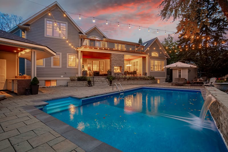 Luxury Backyard Oasis at Twilight Sunset with large patio and unground pool with waterfall